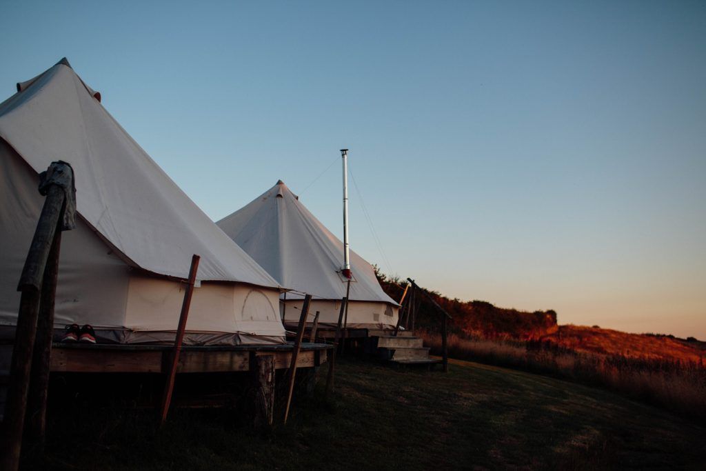 White event tents set up on a hillside during sunset.