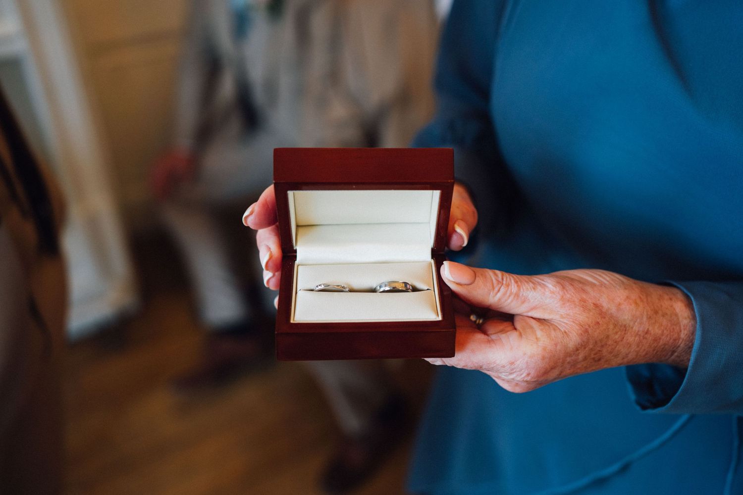 Close-up shot of hands holding a red jewelry box at a formal event.
