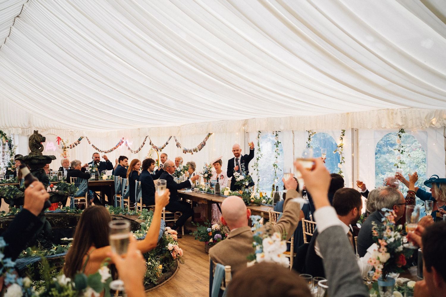 Wedding reception inside an elegant white marquee tent with tables and festive lighting.