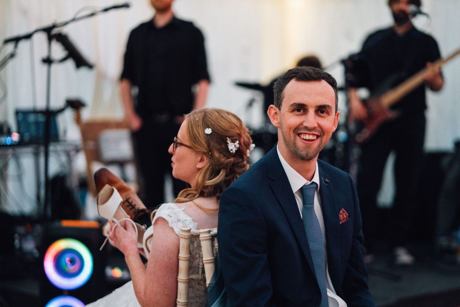 Wedding guests dance and celebrate together on an illuminated dance floor during an evening reception.