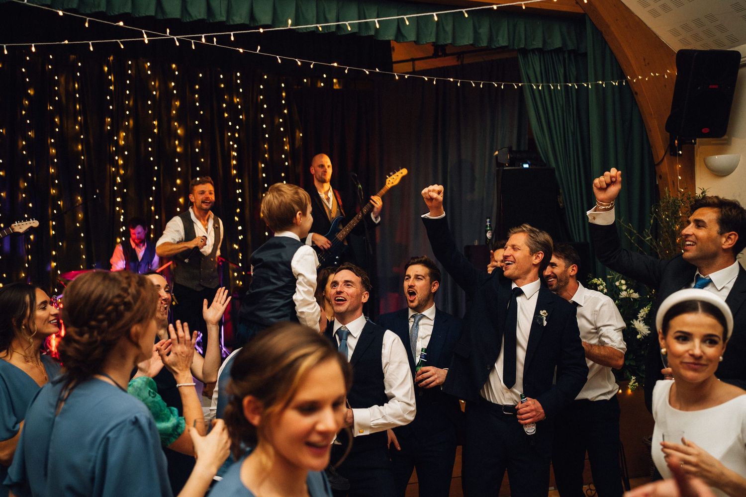 Wedding reception dance floor with string lights and guests dancing under decorative lighting.