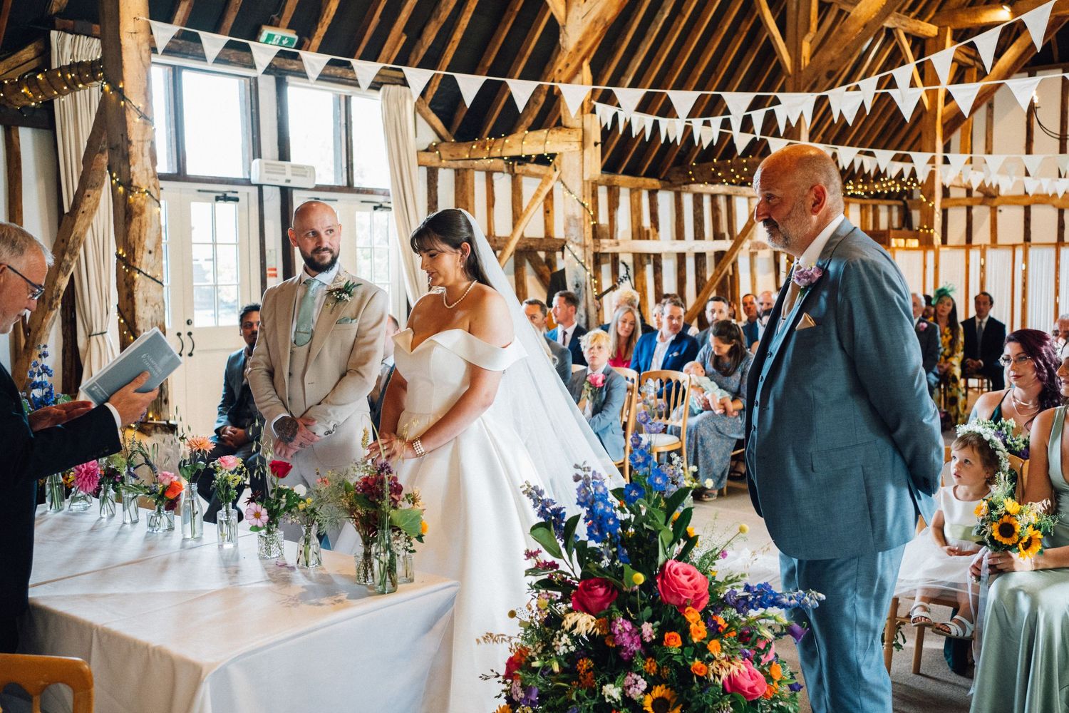 Rustic barn wedding reception venue decorated with white bunting and natural light streaming through windows.