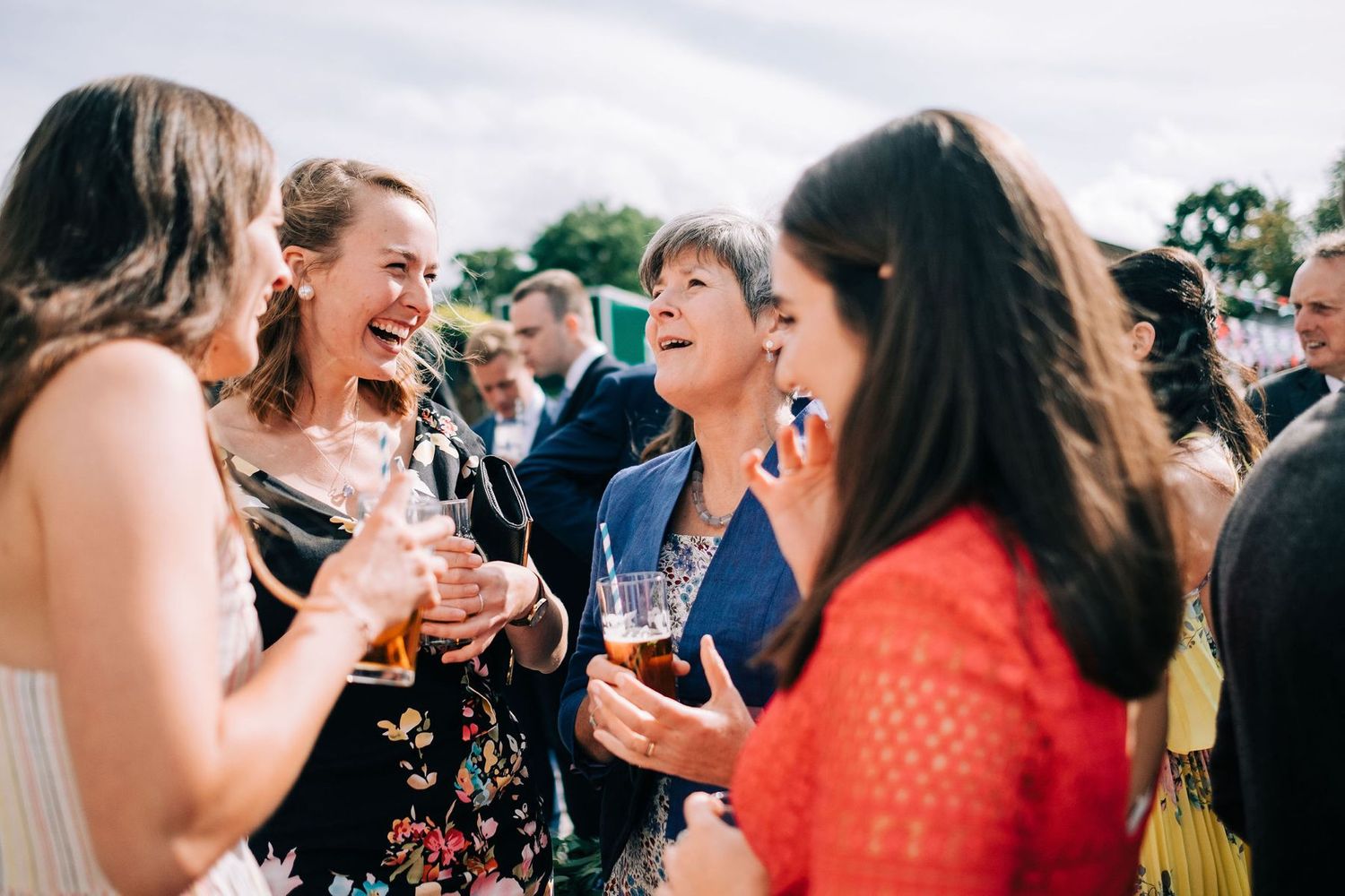 Wedding guests laugh and celebrate during an outdoor reception gathering.