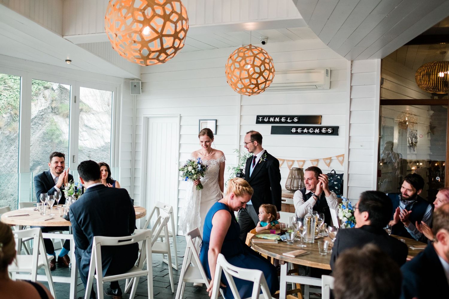 Modern restaurant interior with wooden beams and decorative orange pendant lights.