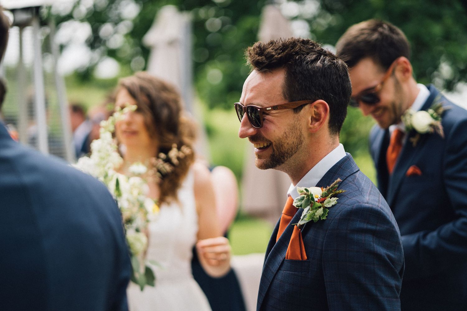 Wedding guests laughing and smiling together during an outdoor celebration.