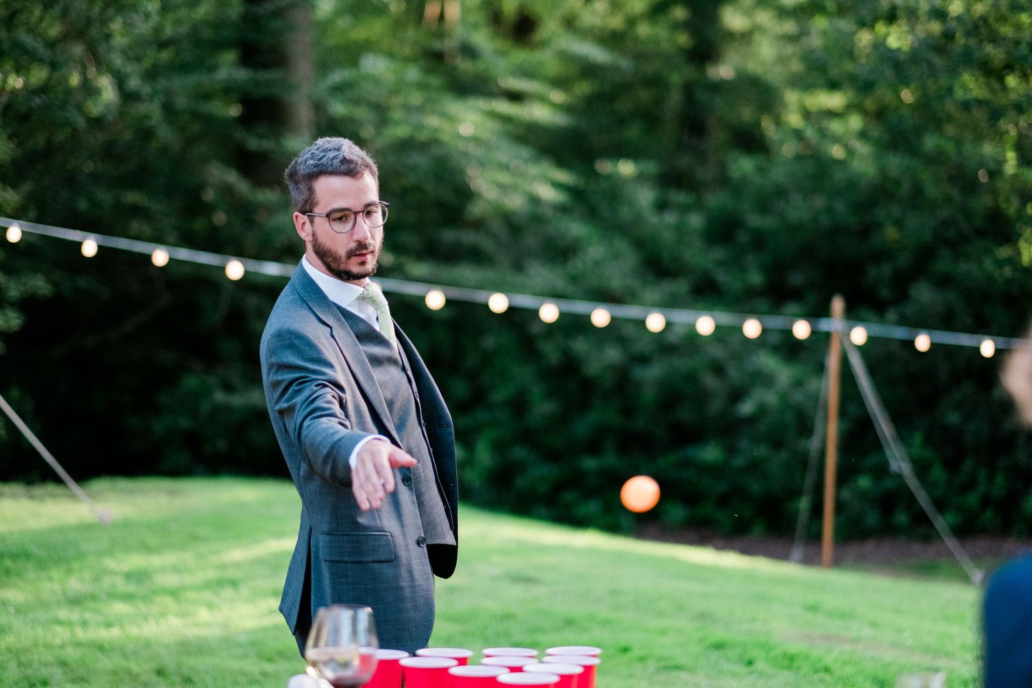 Outdoor wedding venue with string lights and lawn games set up at dusk.