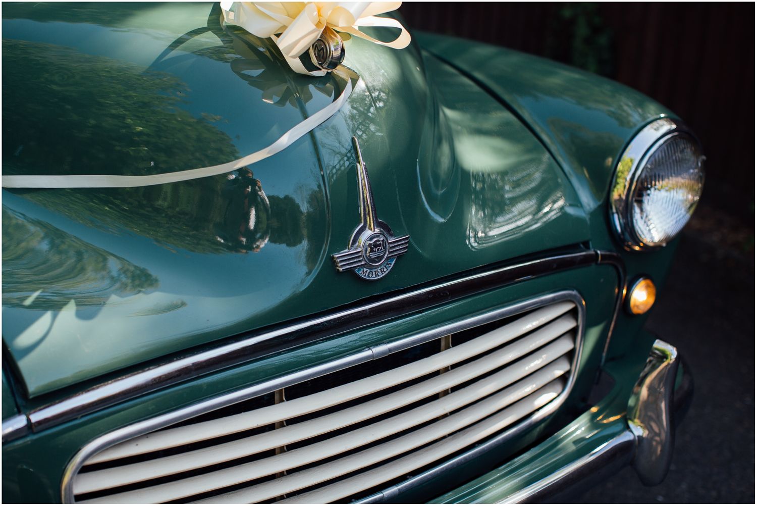 Close-up detail of a vintage Morris Minor's green hood and chrome grille.