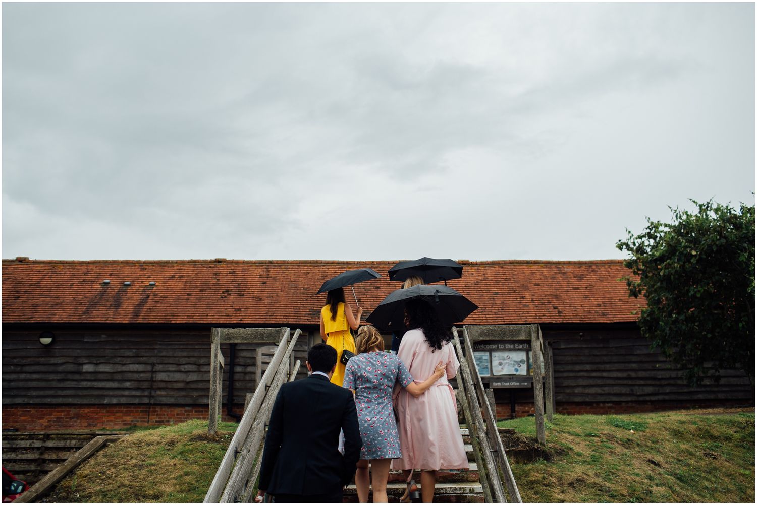 Panoramic view of a countryside barn venue with green fields and cloudy sky.