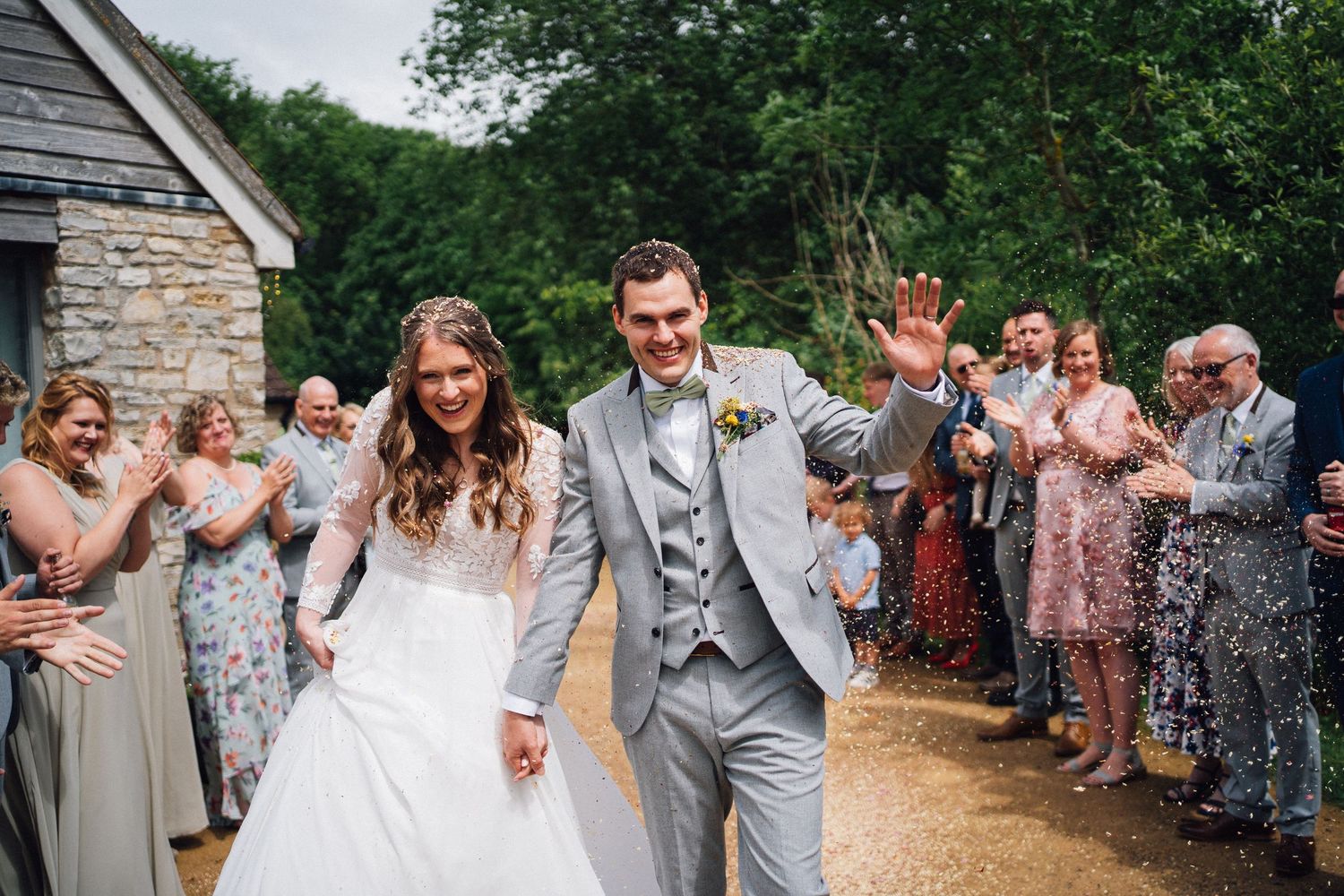 Wedding exit with guests throwing confetti as couple walks down pathway.