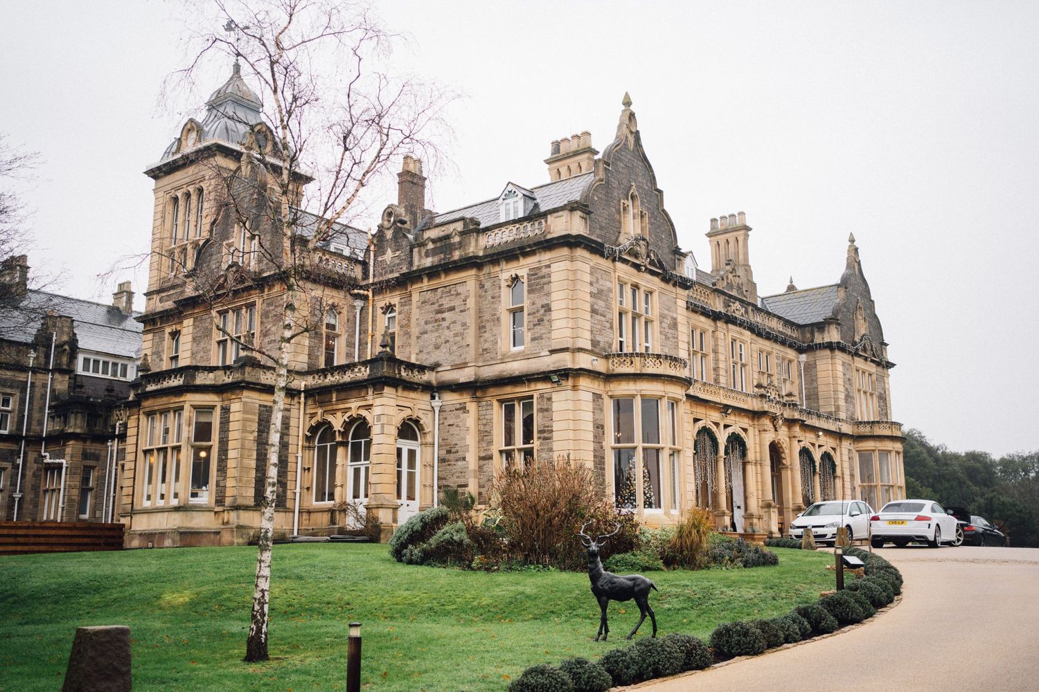 Exterior view of a grand Victorian Gothic style mansion with ornate architecture and manicured grounds.