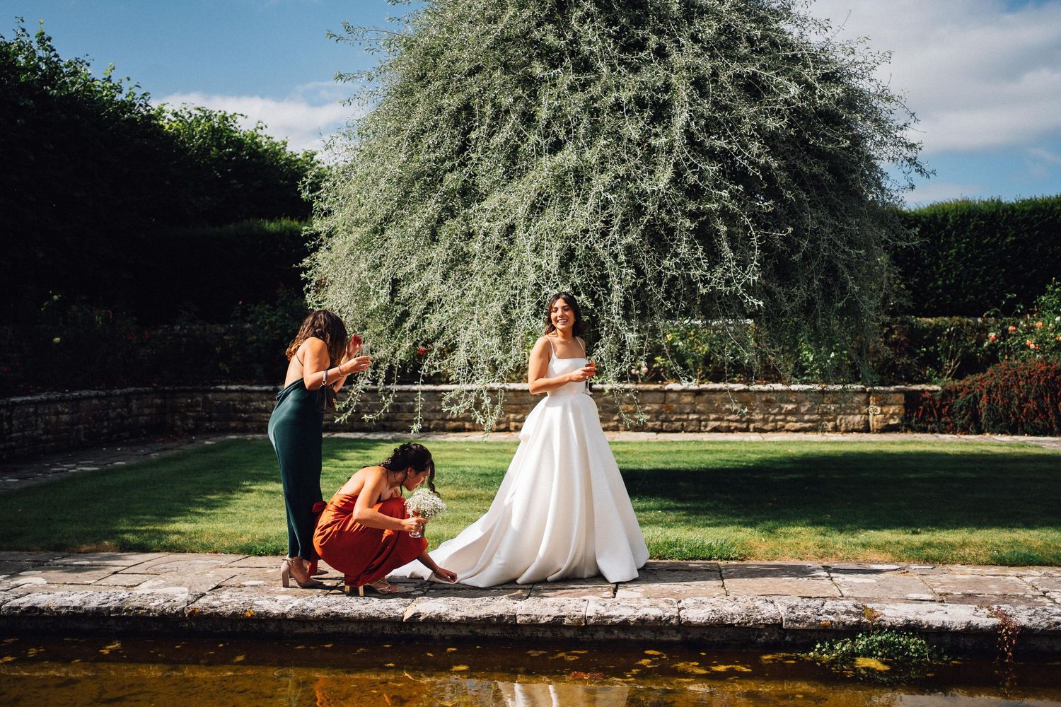 Beautiful garden venue with stone walls and lush greenery under blue skies.
