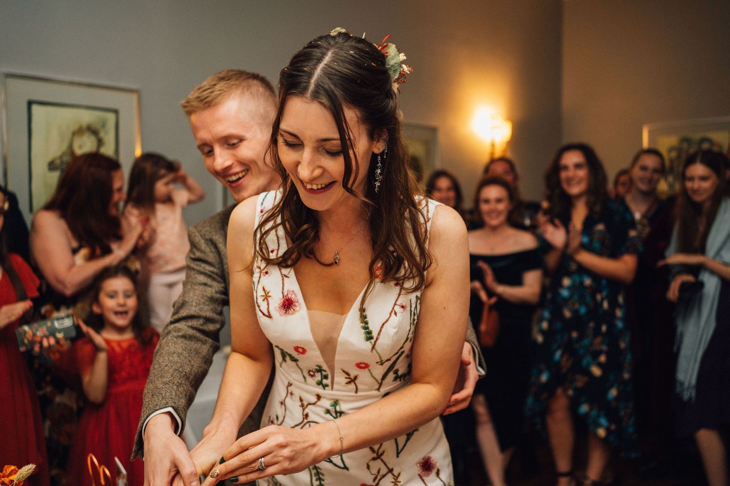 Wedding guests dance and celebrate together on a dimly lit dance floor at an evening reception.