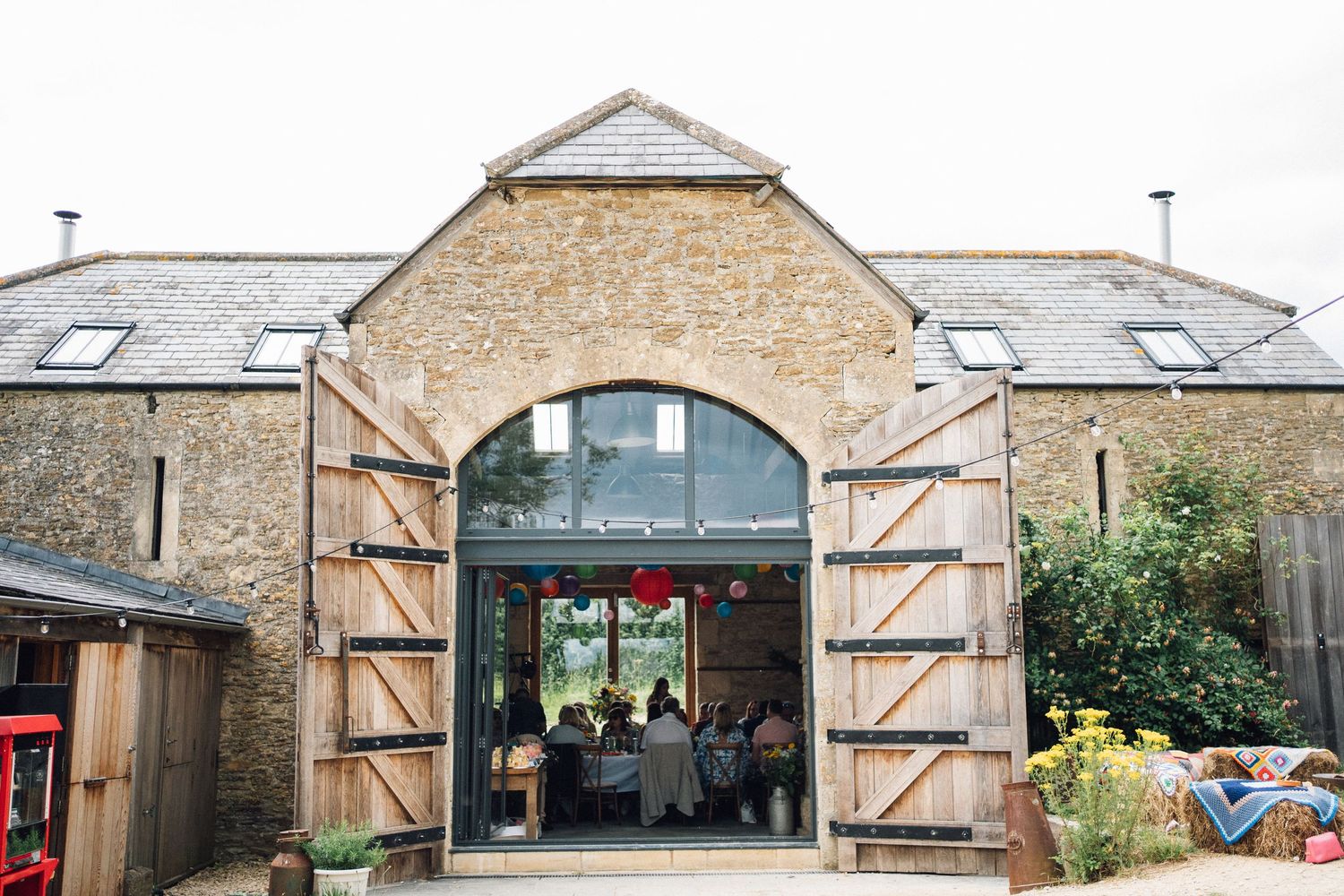 Exterior view of a converted barn wedding venue with large wooden doors and stone walls.
