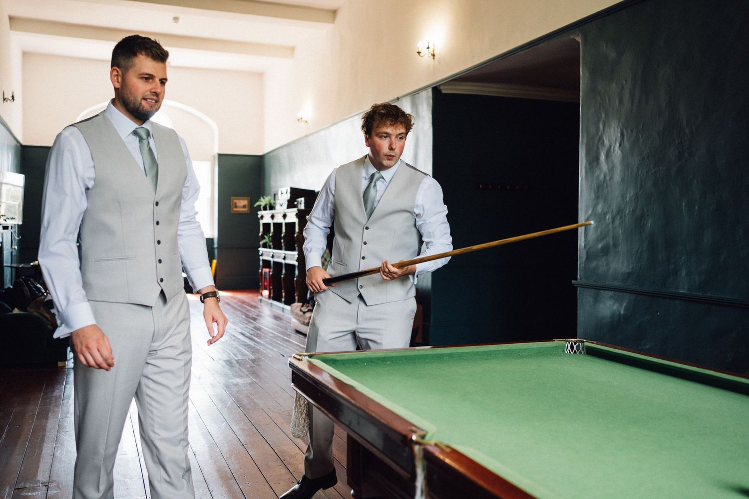 Wedding party playing pool in formal attire at an elegant billiards room.