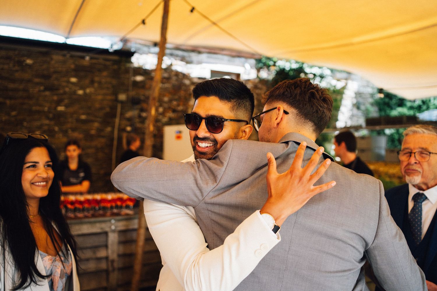 Guests mingle and socialize under a yellow tent during a festive outdoor gathering.