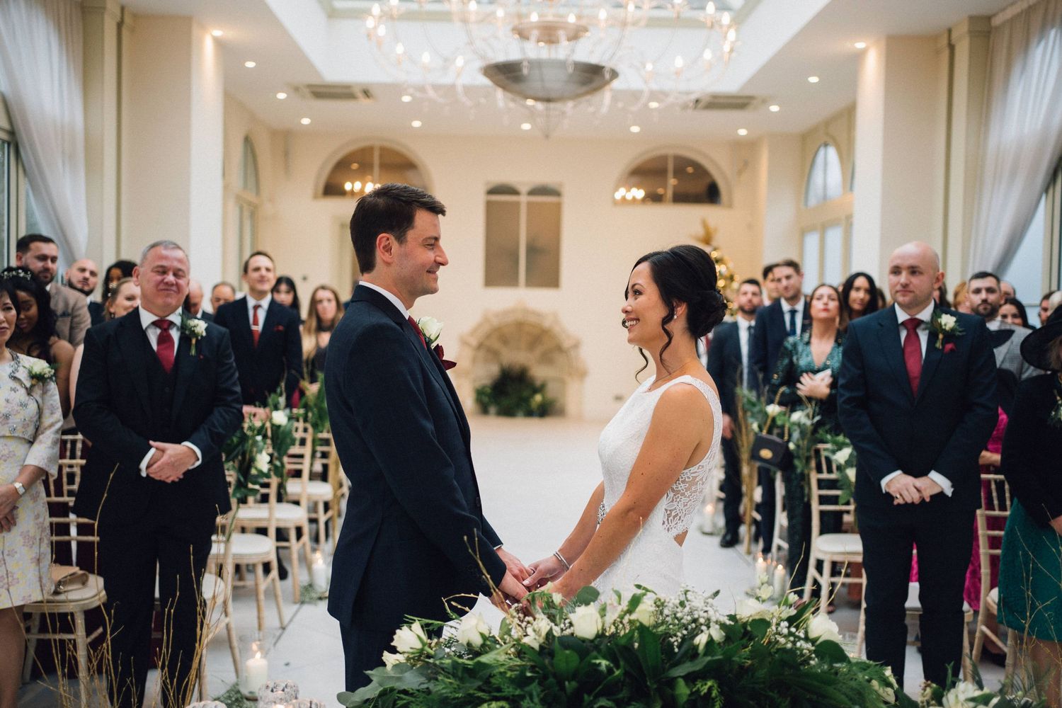 Wedding celebration panorama showing guests and decor in a luxurious white ballroom setting.