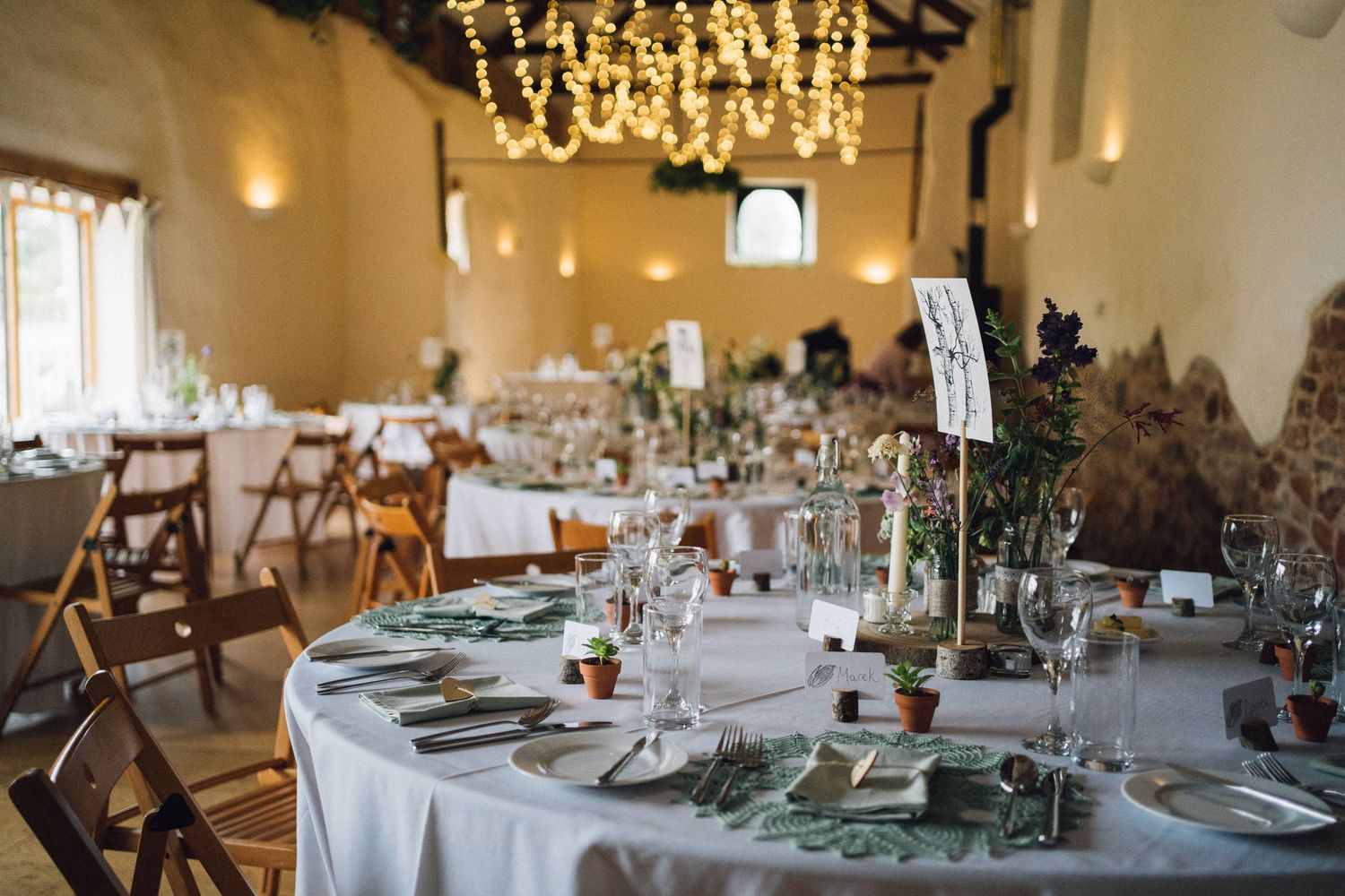 Elegant wedding reception room with chandeliers and tables set for dining.