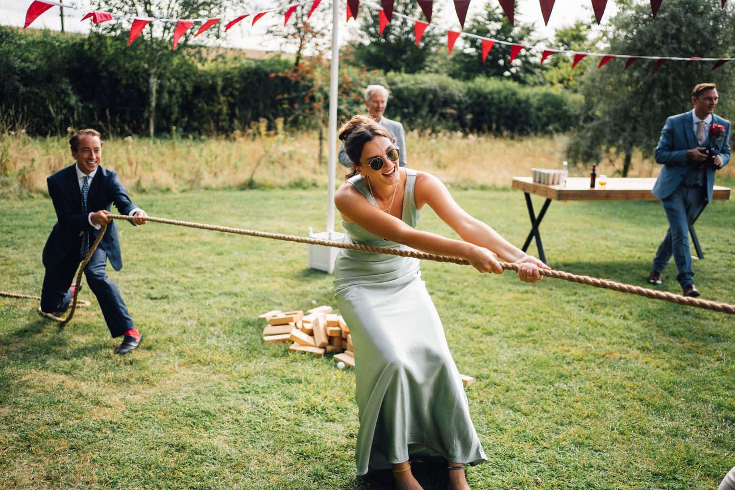 Wedding party playing tug of war outdoors on a sunny day.