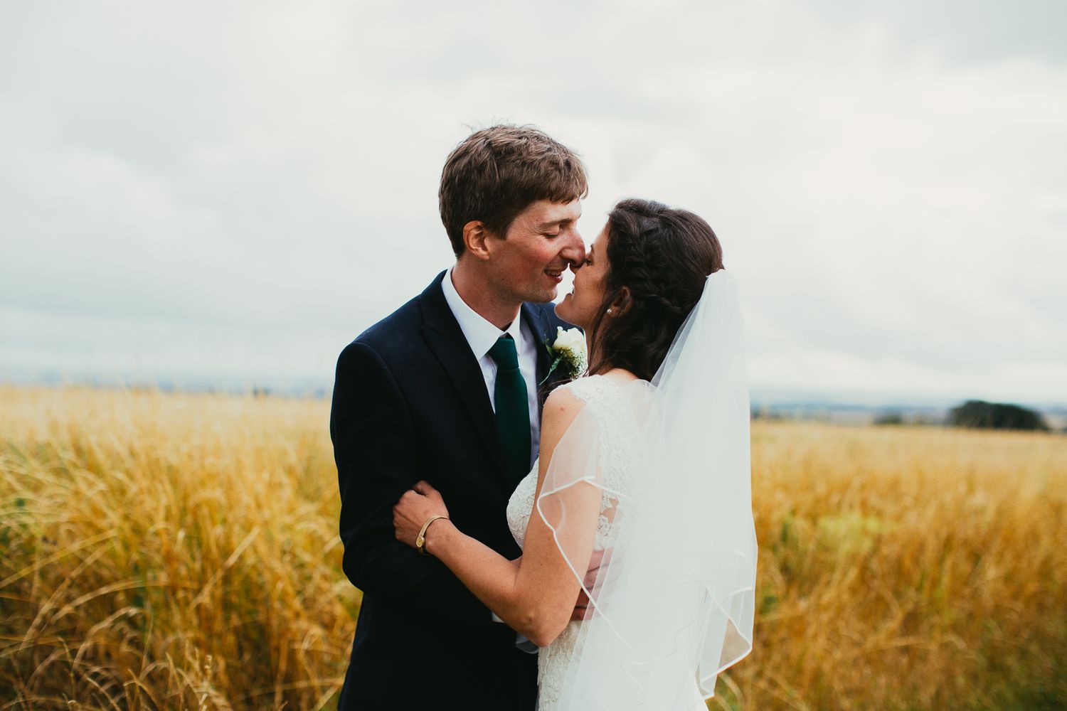 Romantic couple shares a tender moment in a golden wheat field during their wedding photo session in Nailsea, Bristol by Jacob Boodrie Photo