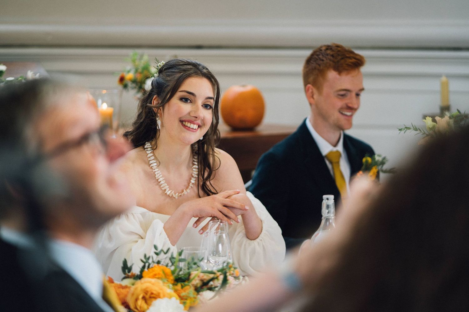 Wedding reception table settings feature bright orange pumpkins and floral centerpieces.