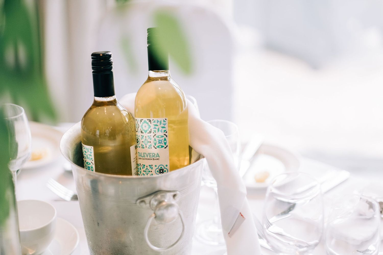 Wine bottles and table settings arranged for an upscale wedding reception.