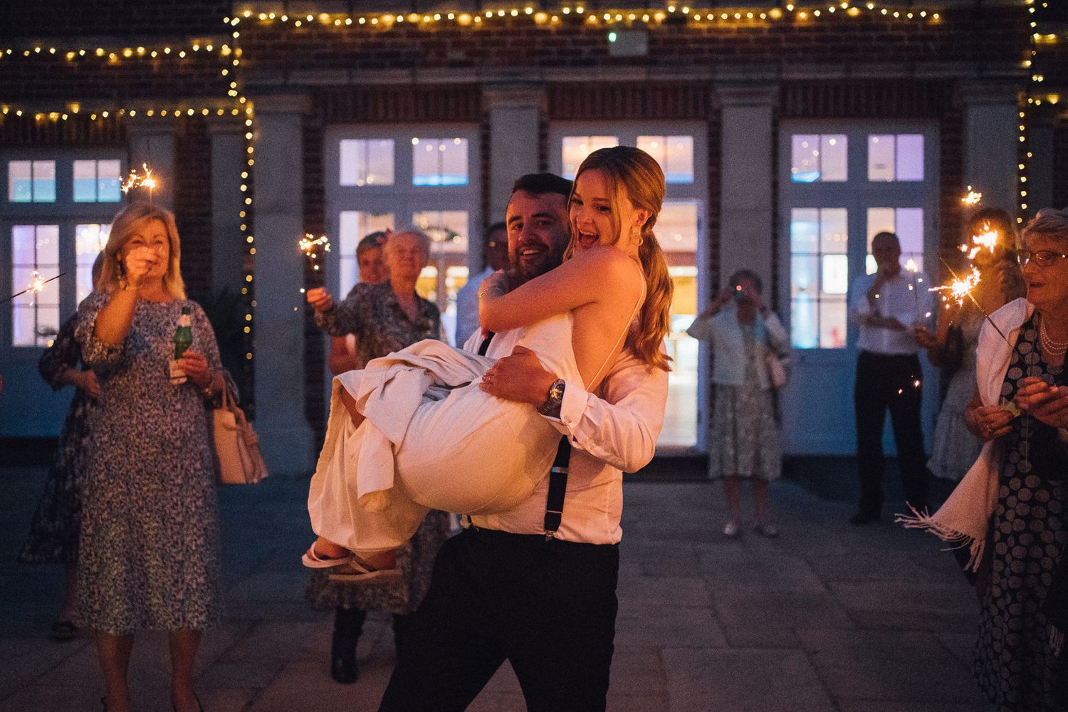 Evening wedding celebration with string lights and large windows creating an intimate ambiance.