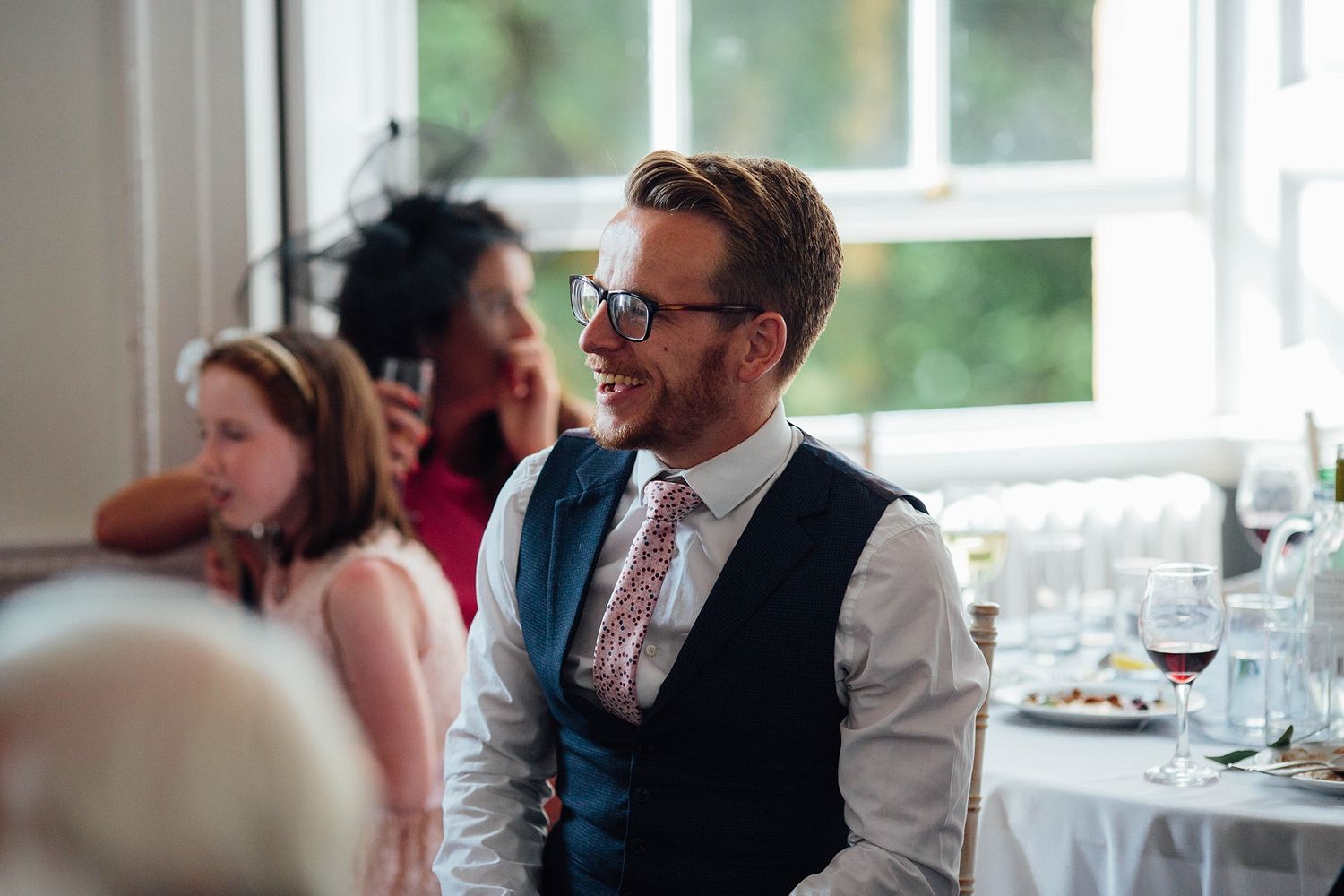 Wedding reception venue with bright windows and elegant table settings.