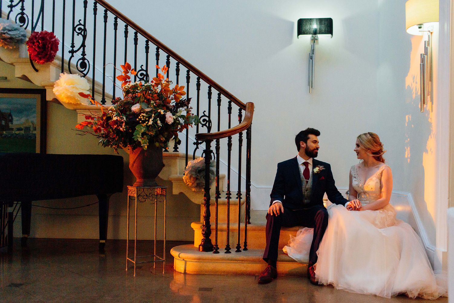 A couple walks down an elegant staircase at their wedding celebration.