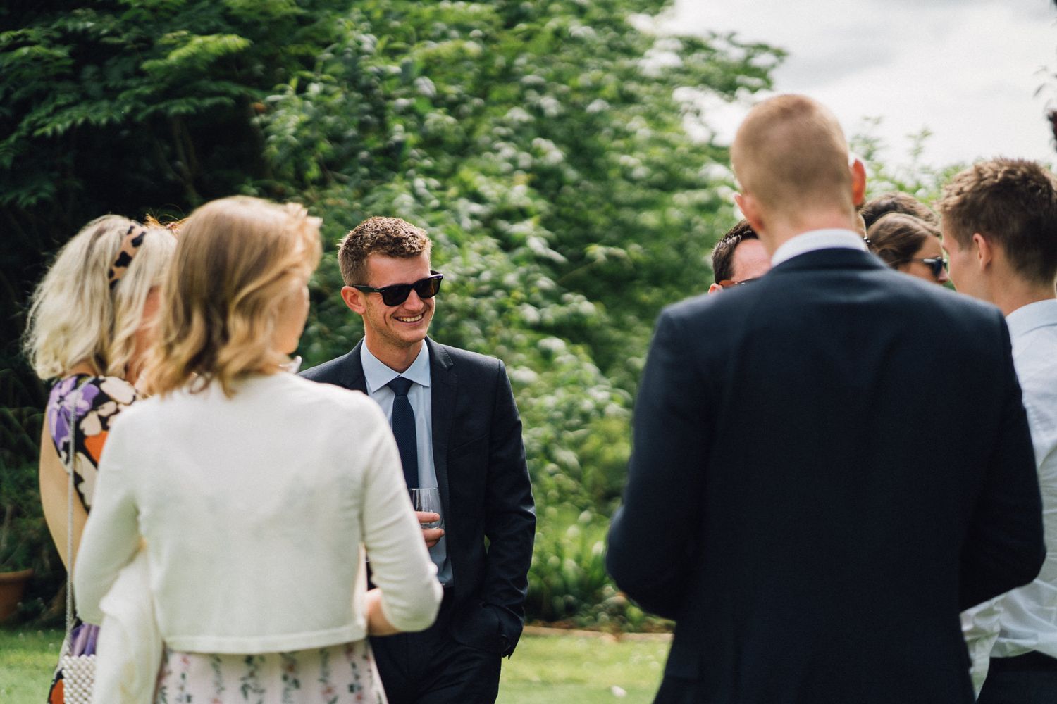 Elegant wedding guests mingle during an outdoor garden reception.