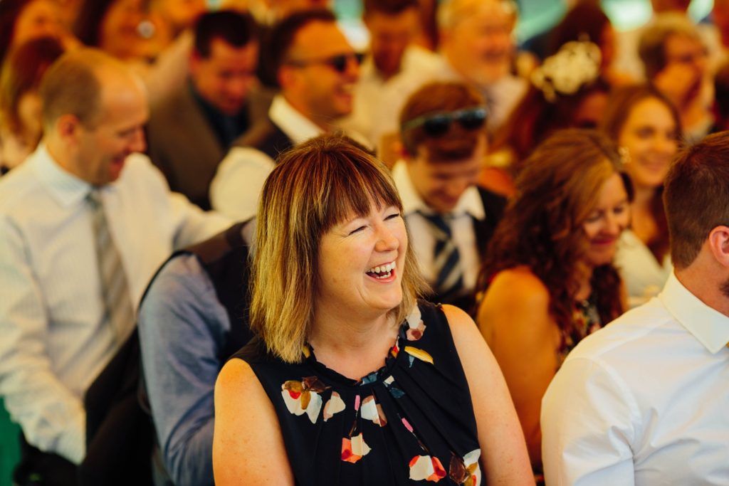 Wedding guests smile and laugh during a joyful reception celebration.