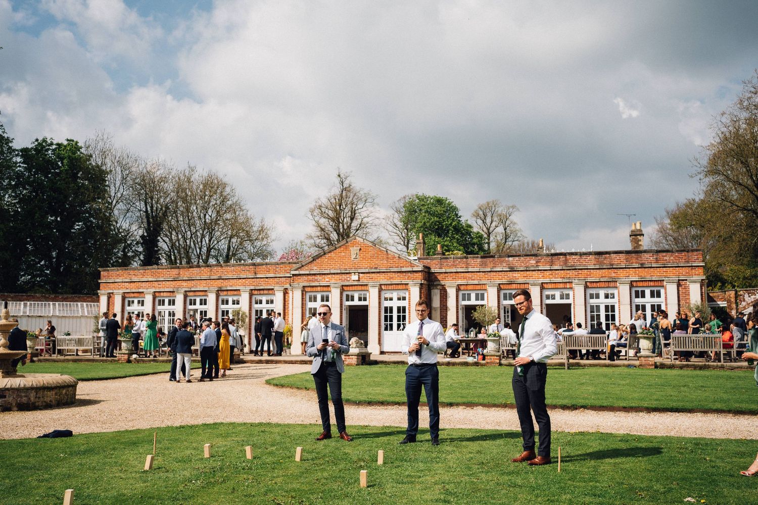 Elegant wedding venue with red brick buildings and manicured lawns on a cloudy day.