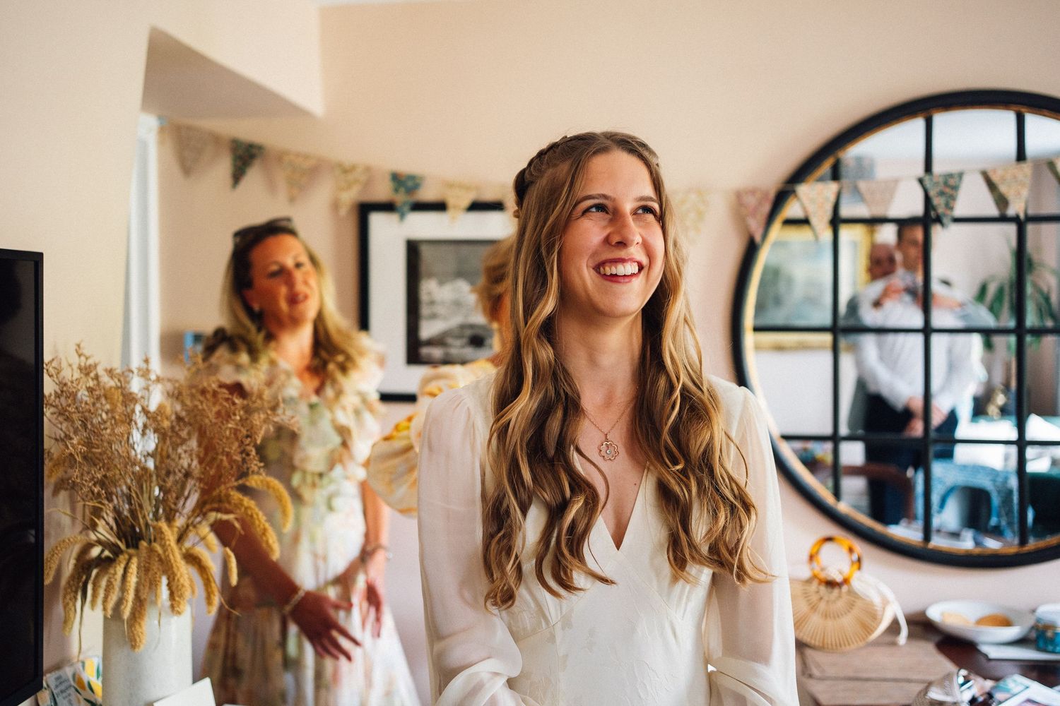 A joyful moment captured during wedding preparations in a bright room with a round window and dried floral decor.