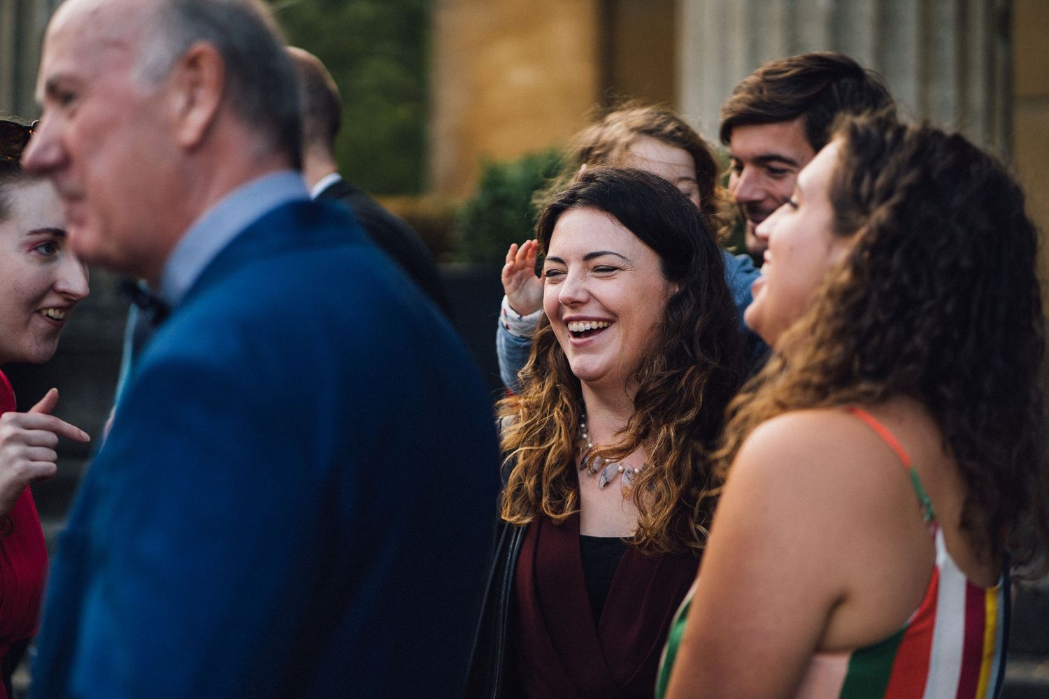 Joyful wedding guests laughing and socializing during an outdoor reception.