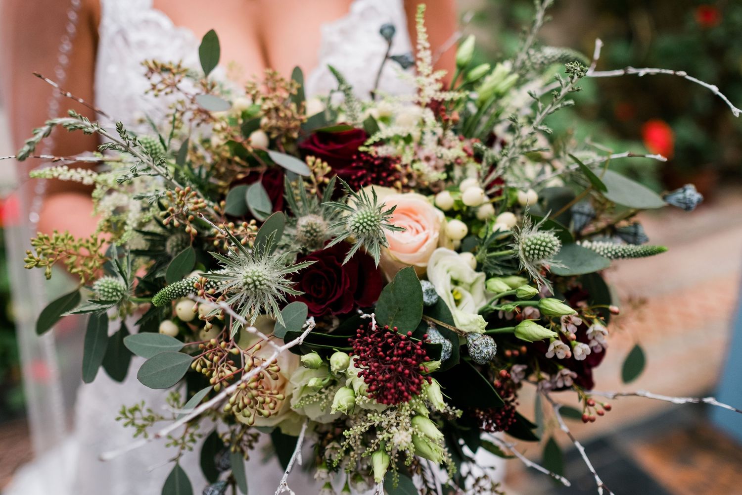 Elegant wedding bouquet featuring burgundy and blush flowers with cascading greenery.
