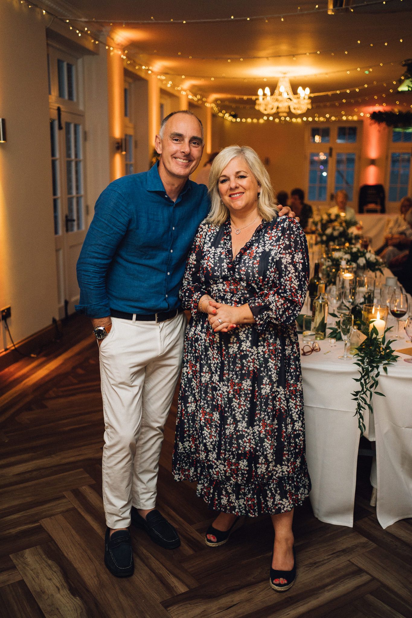 Reception guests enjoying themselves at decorated wedding tables with floral centerpieces.