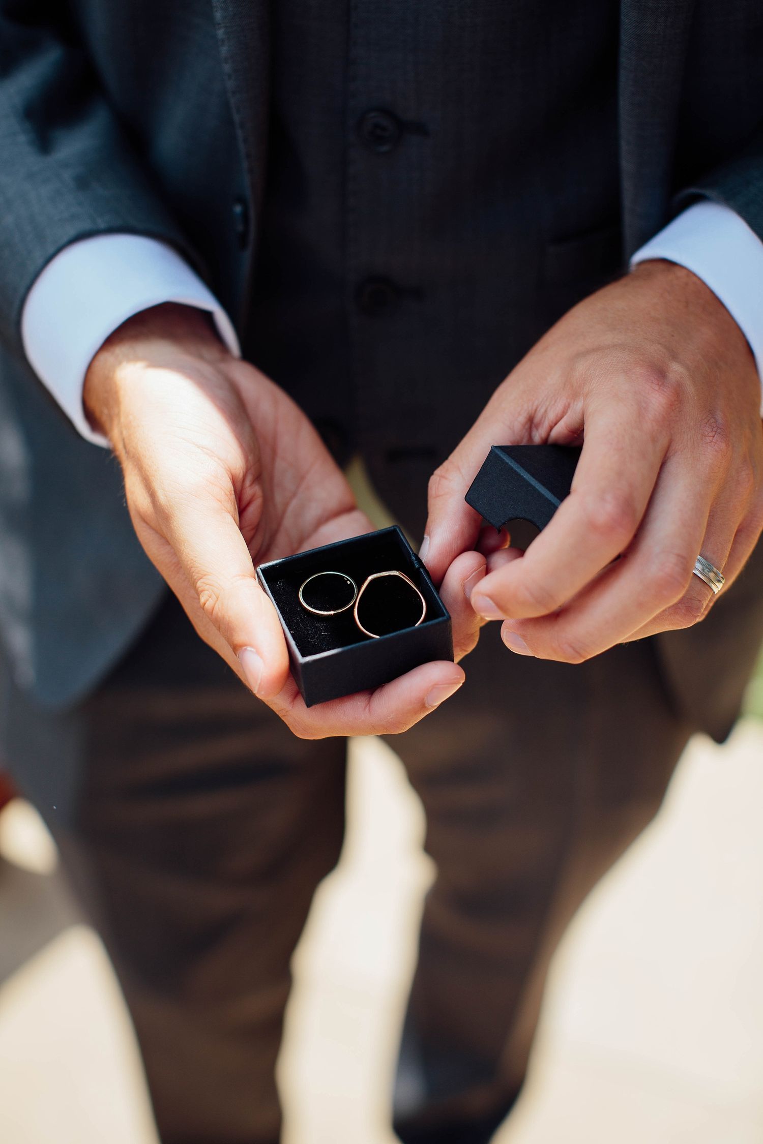 Close-up shot of hands holding wedding rings in natural lighting.