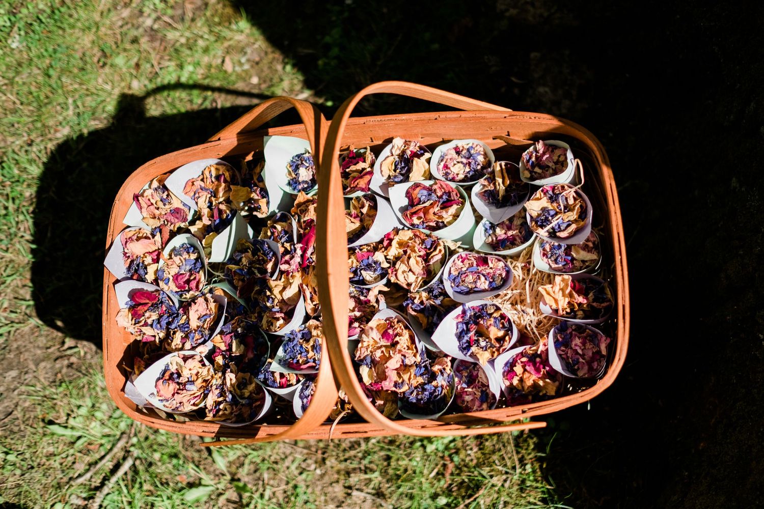 Rustic wooden basket filled with colorful floral bouquets sitting on grass.