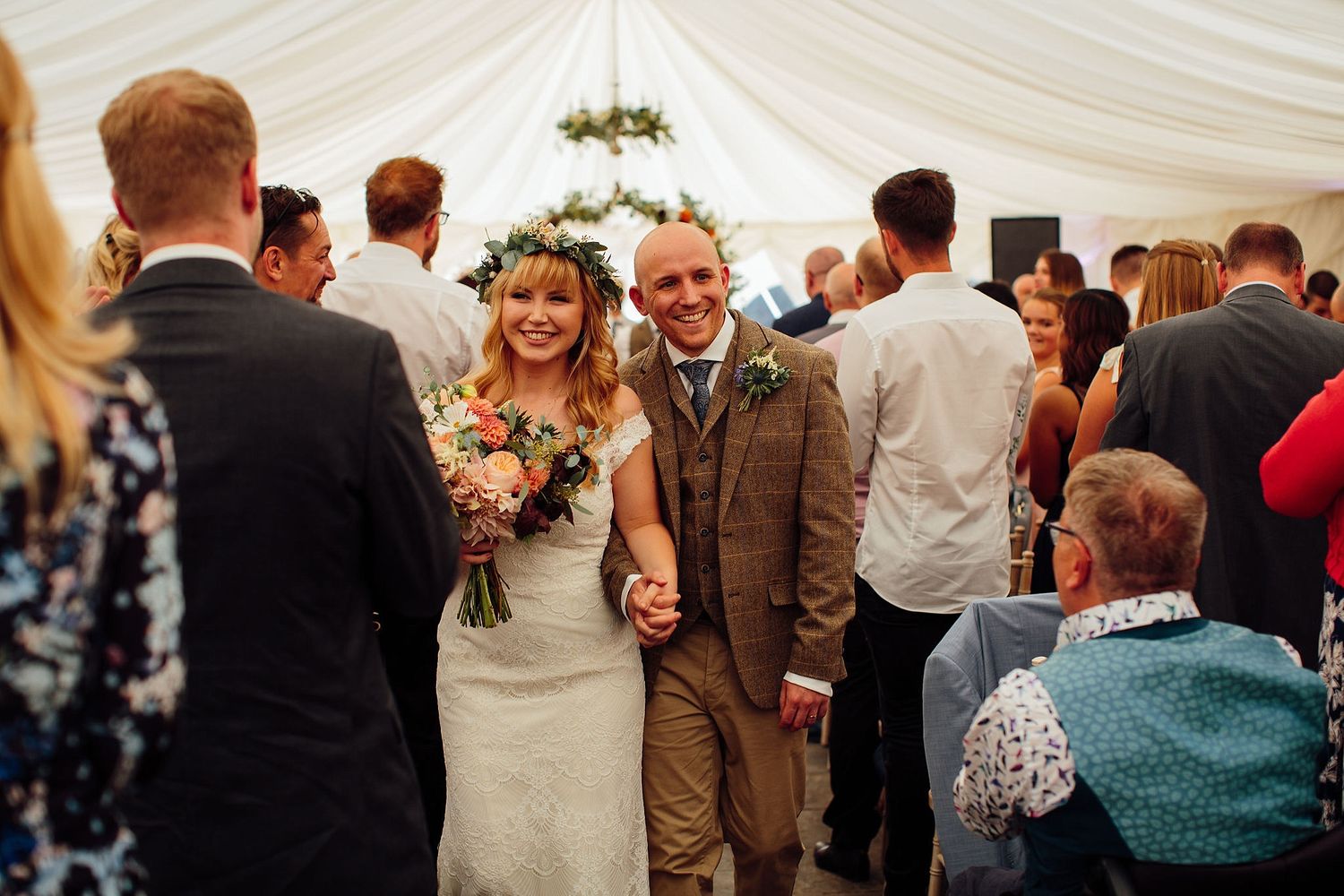 Wedding celebration with guests mingling under white tent decorations.