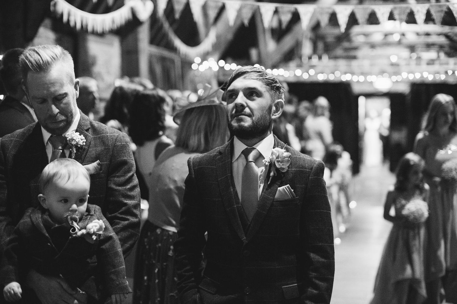 Black and white photo of wedding guests mingling during reception.