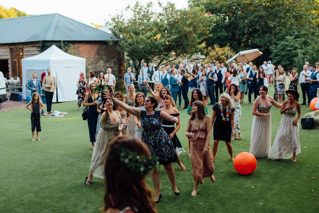 Wedding party and guests gather on a green lawn for outdoor celebration activities.
