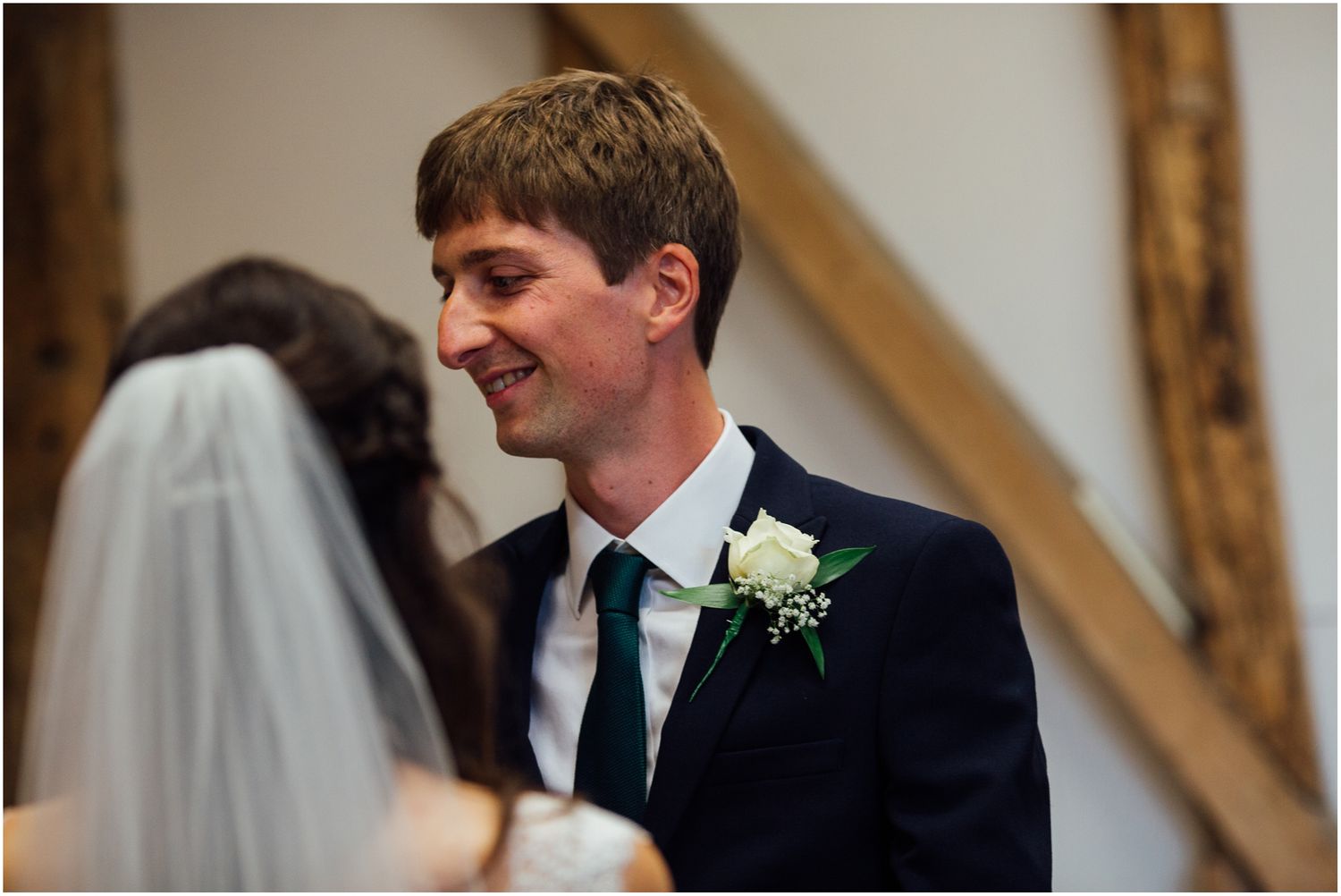 Close-up shot of wedding couple during ceremony in rustic barn setting.