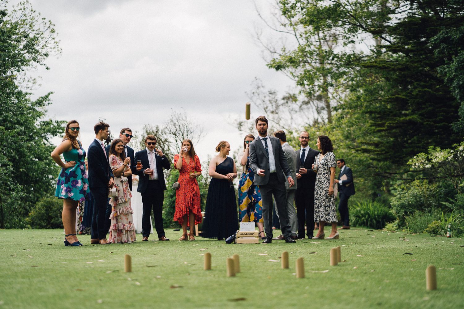 Wedding guests gather on a grassy lawn for outdoor garden party games.