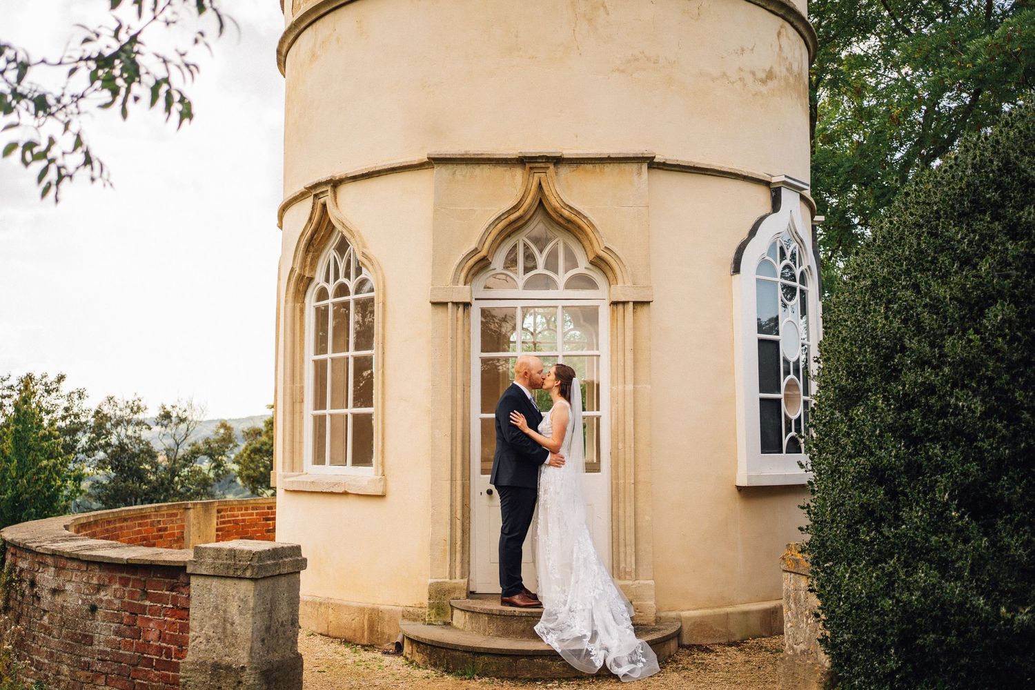 Wedding couple standing outside a cream-colored historic building with arched windows.