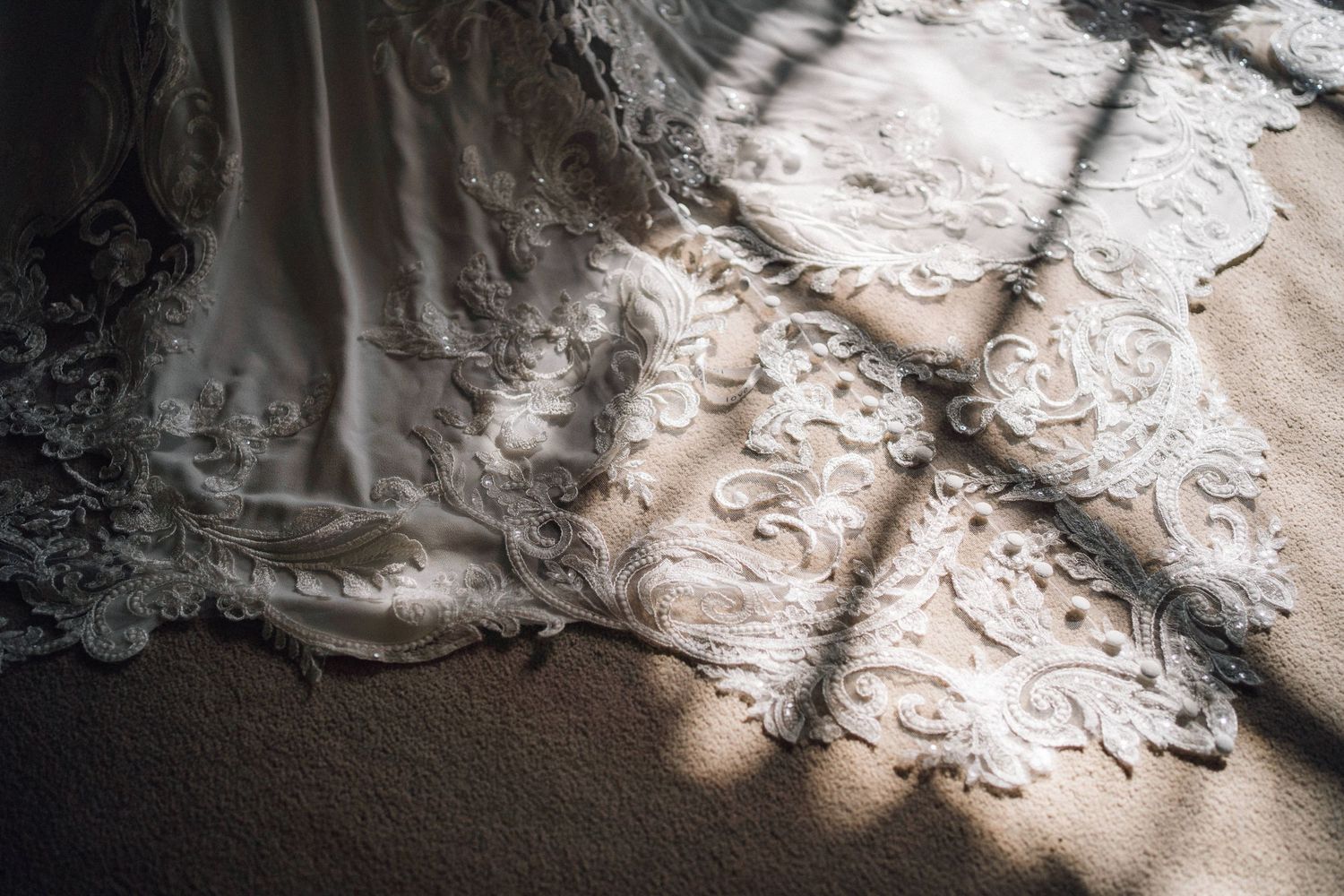 Intricate lace details of a wedding dress train illuminated by soft natural light.