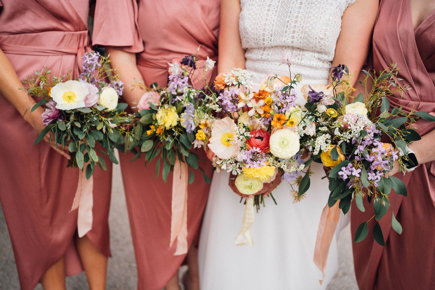 Row of colorful summer wedding bouquets with wildflowers and greenery.