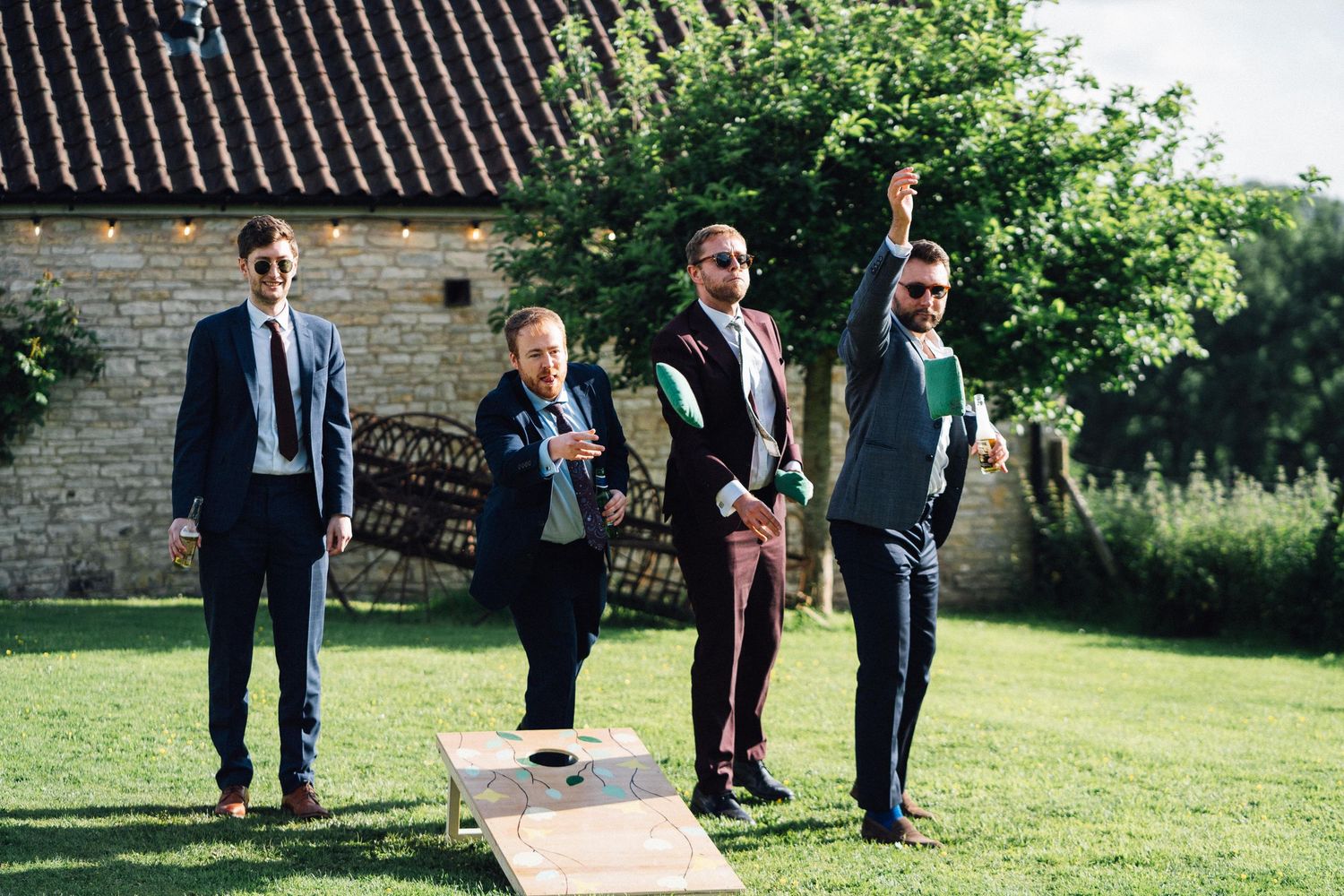 Wedding guests walking along stone path in sunny garden setting.