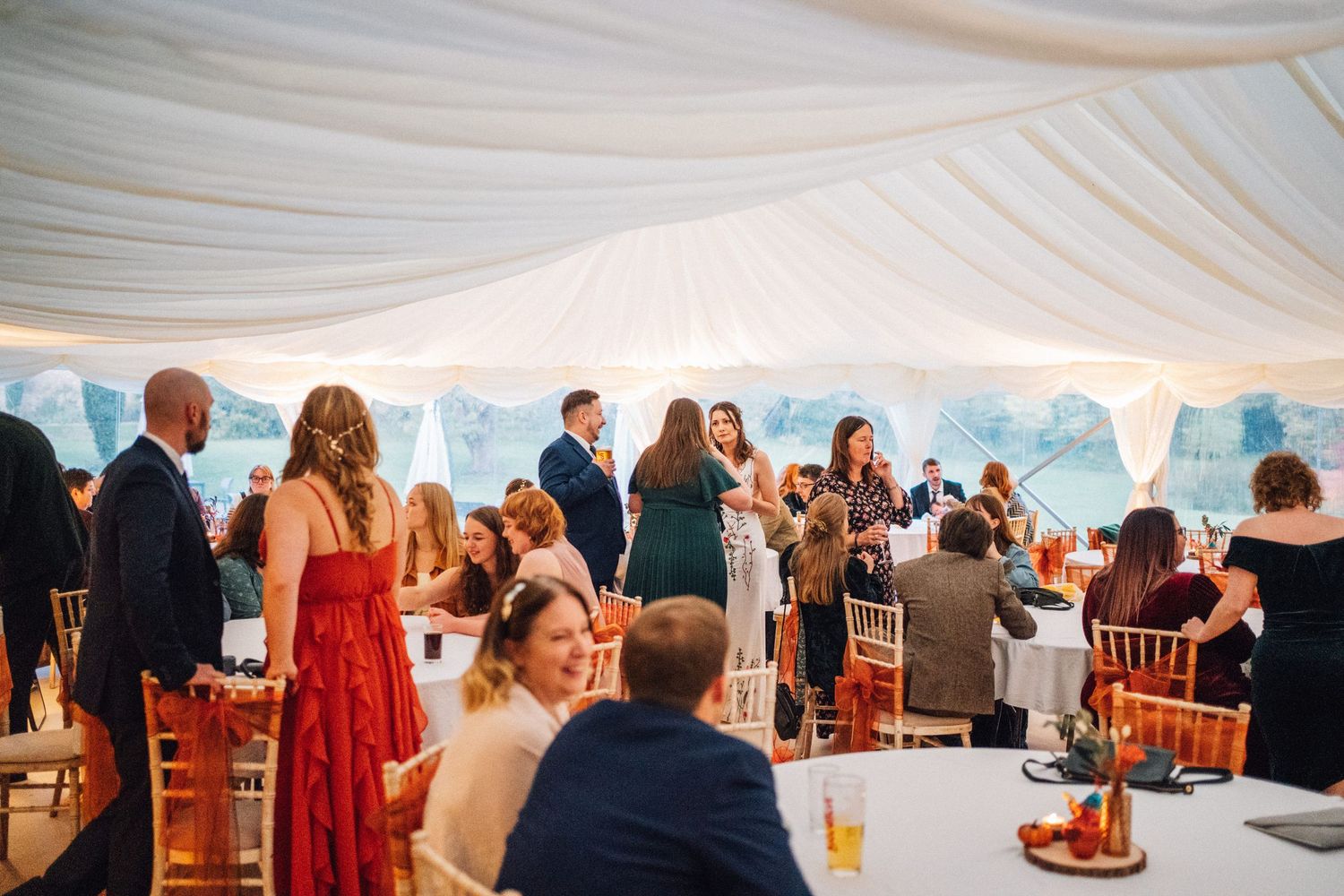 Wedding reception setup under an elegant white tent with tables and chairs arranged for guests.