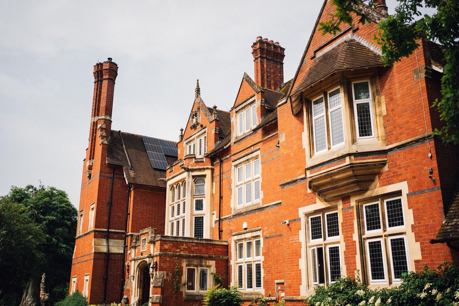 Exterior view of a traditional red brick Victorian mansion with ornate architectural details and tall windows.