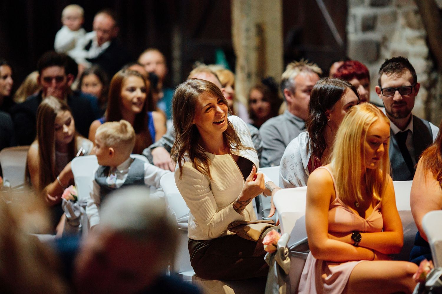 Guests laugh and enjoy themselves during an indoor wedding celebration.