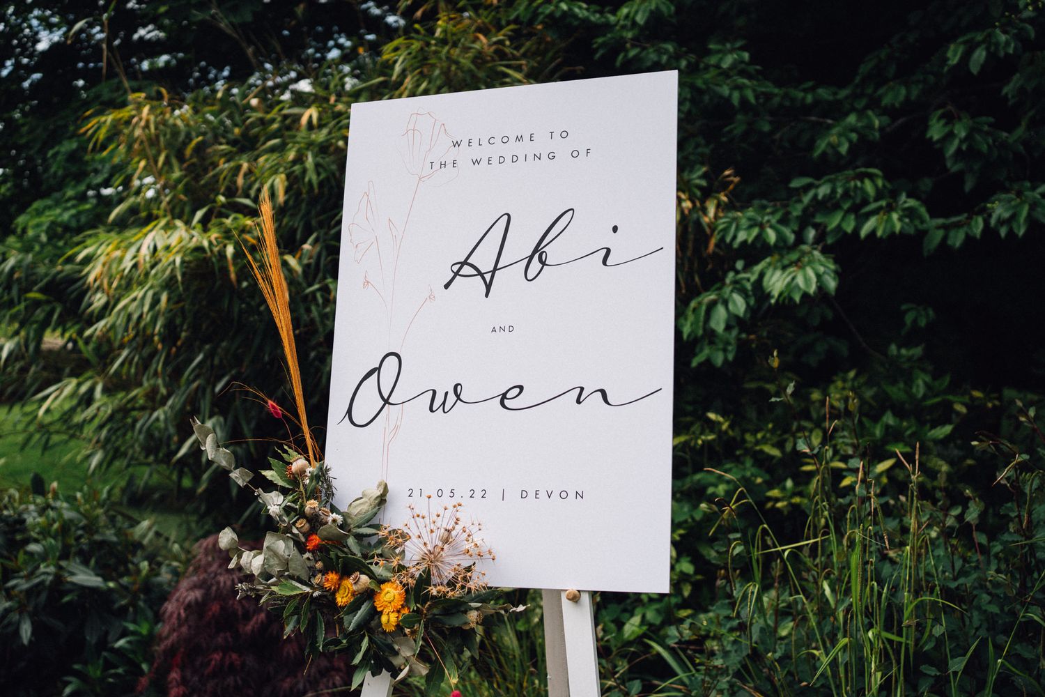 Elegant wedding signage displayed in a garden setting with lush greenery.